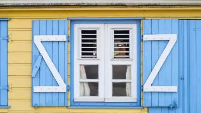photo d'une maison coloniale jaune avec volet bleu
